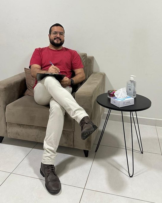 Giovane sentado na poltrona do consultório, com a prancheta de anotações