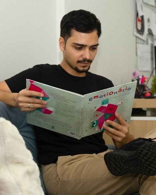 Saymon lendo um livro de emoções no consultório